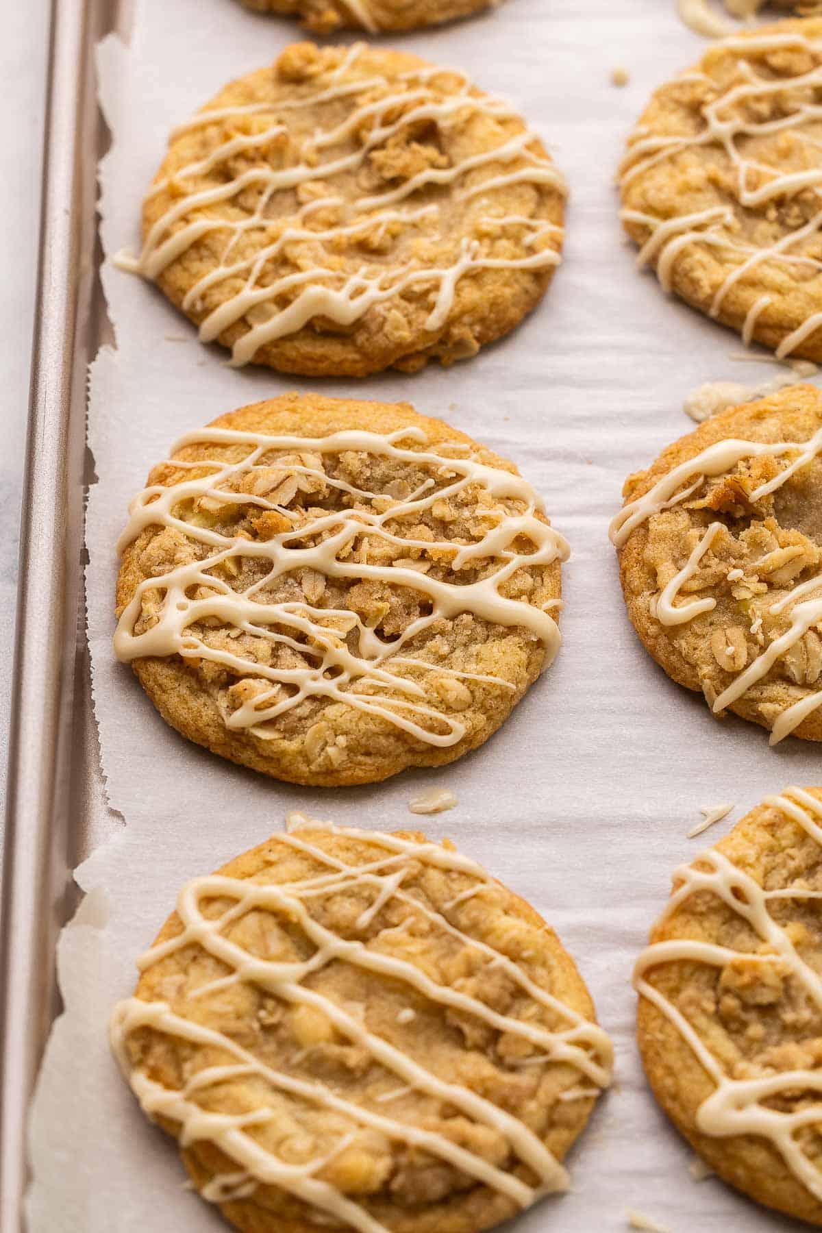 close up of apple crisp cookies with maple glaze on sheet pan.
