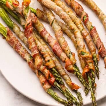 bacon wrapped asparagus on a white plate.