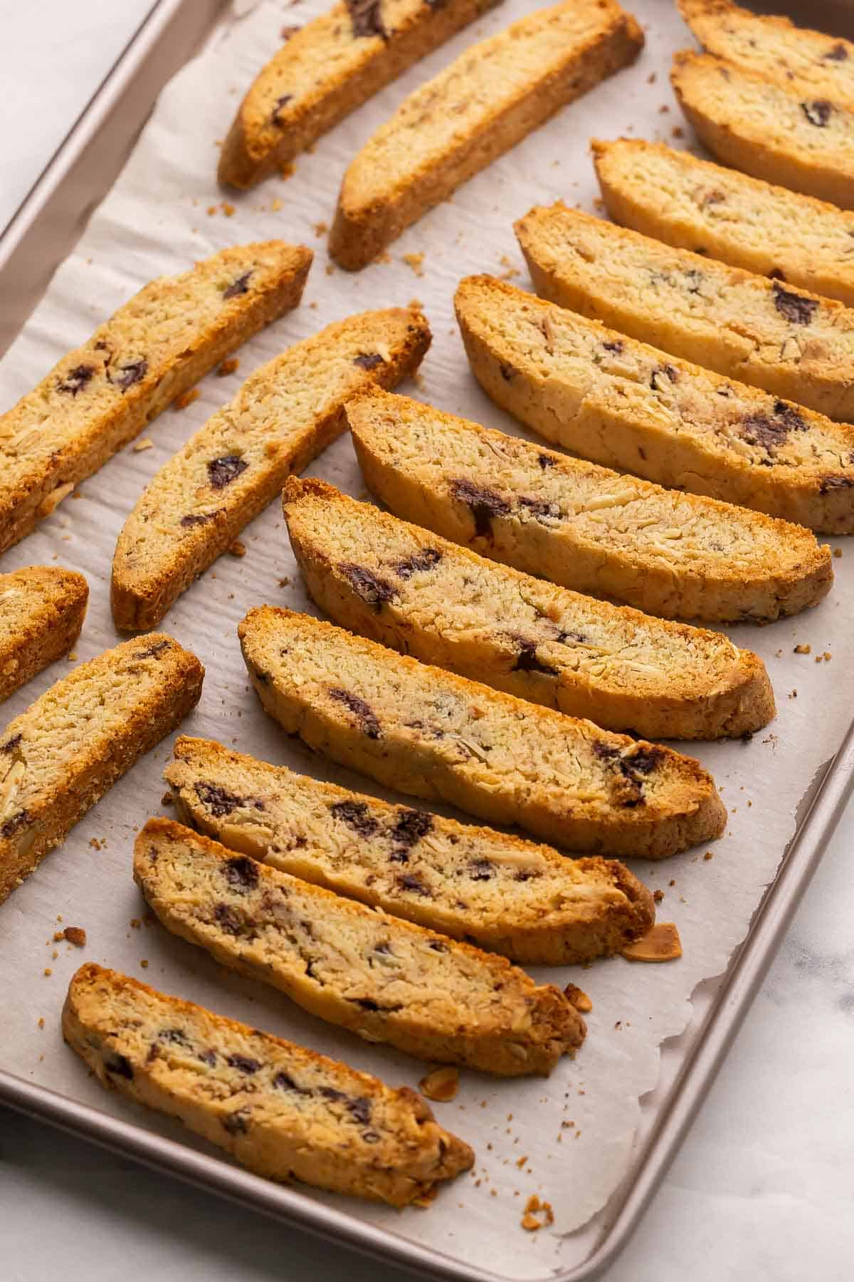 These Chocolate Almond Biscotti cookies are twice-baked Italian cookies made with basic pantry staples and can be customized with your favorite add-ins. So easy to make and perfect for dunking in a cup of coffee! #cookie #dessert #recipe | baking recipe | almond biscotti recipe | biscotti cookies | almond cookies | dark chocolate | christmas cookies | italian biscotti slices of biscotti in lined up in pan.