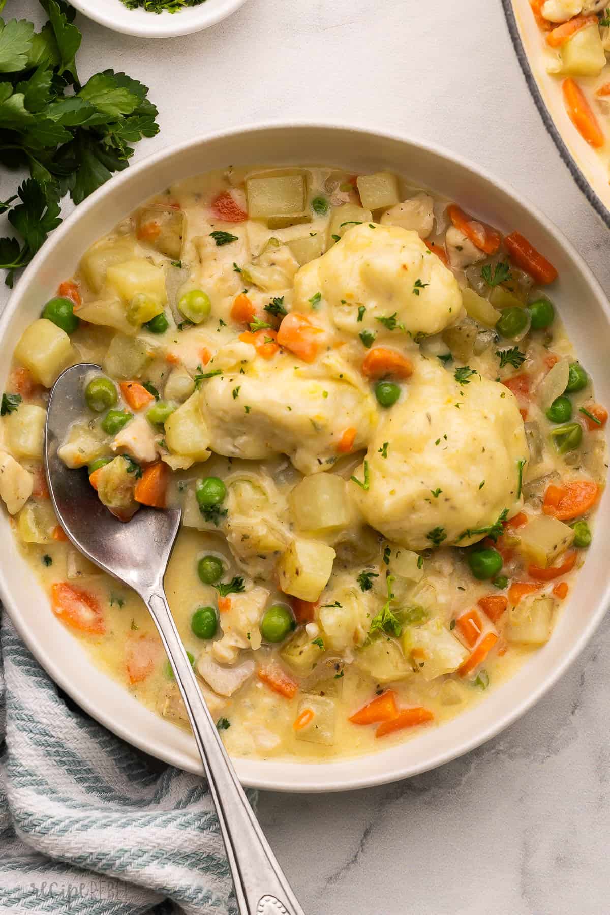 overhead image of bowl of chicken and dumplings with spoon stuck in.