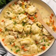square image of chicken and dumplings in a cream colored braiser.