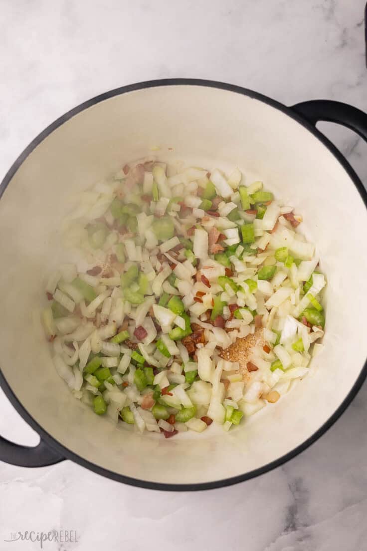 vegetables being sauteed in large black and white pot.