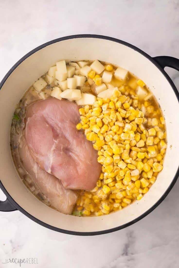 chicken breasts and corn added to other ingredients in soup pot.
