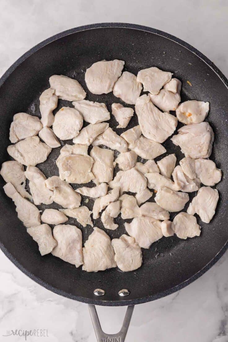 chopped chicken cooked in black frying pan.