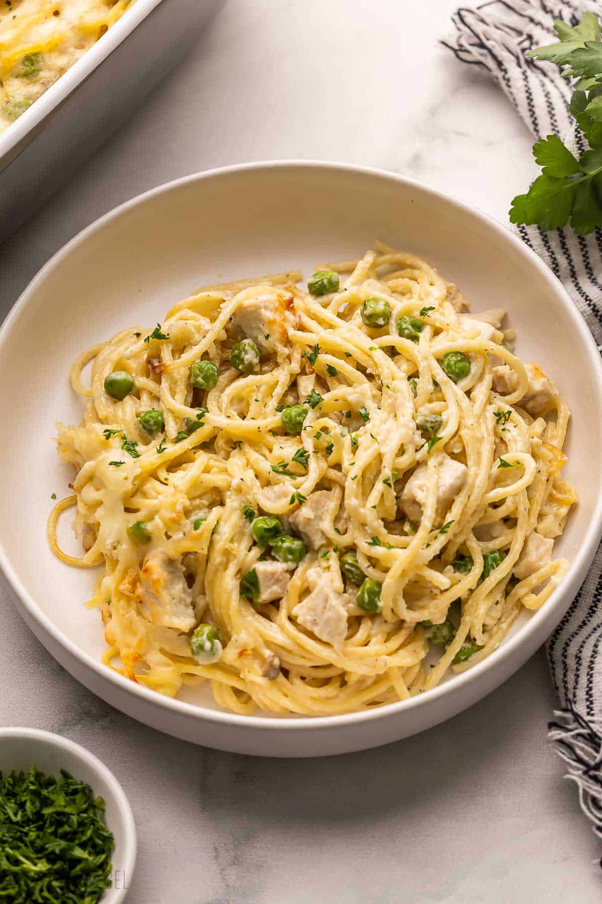 large bowl filled with chicken tetrazzini and parsley beside.