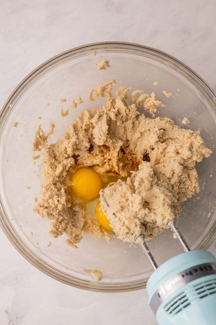 cookie dough in a mixing bowl with eggs added.