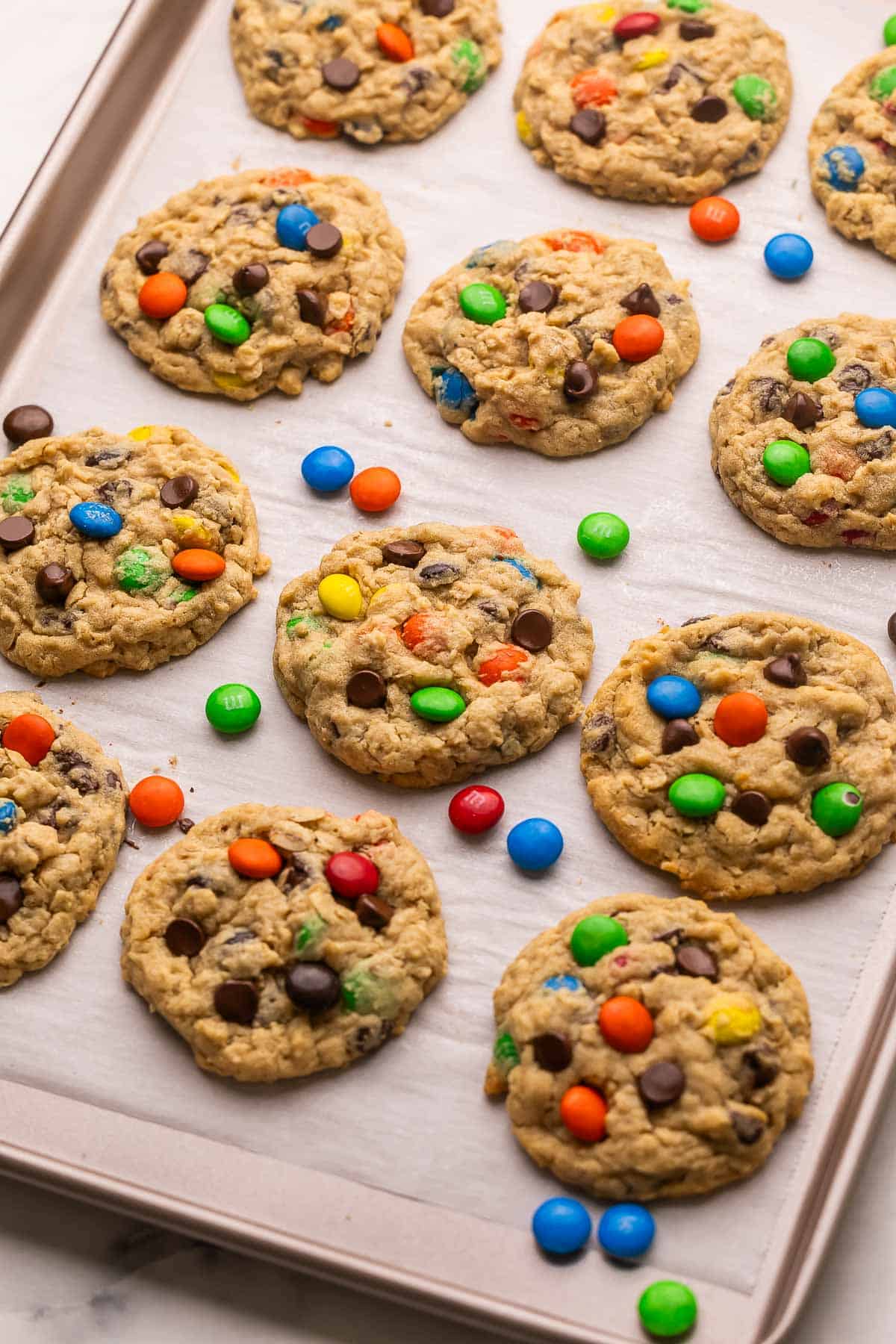 Classic Monster Cookies are loaded with creamy peanut butter, chewy old-fashioned oats, melty chocolate chips, and colorful M&Ms. They're the perfect cookie for those who like a little bit of everything! #cookie #recipe | cookie recipe | cookies recipe | peanut butter cookies | oatmeal cookies | m&m cookies | dessert recipe | baking recipe monster cookies on a parchment lined sheet pan.