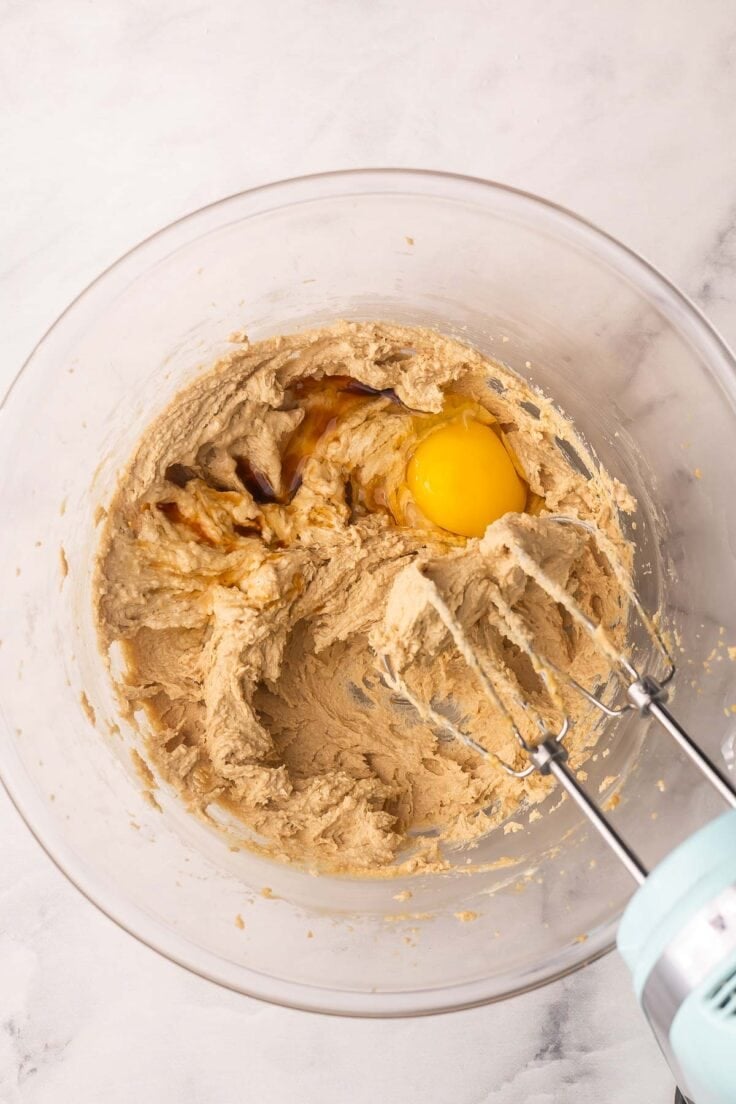 cookie dough in a mixing bowl with an egg added.