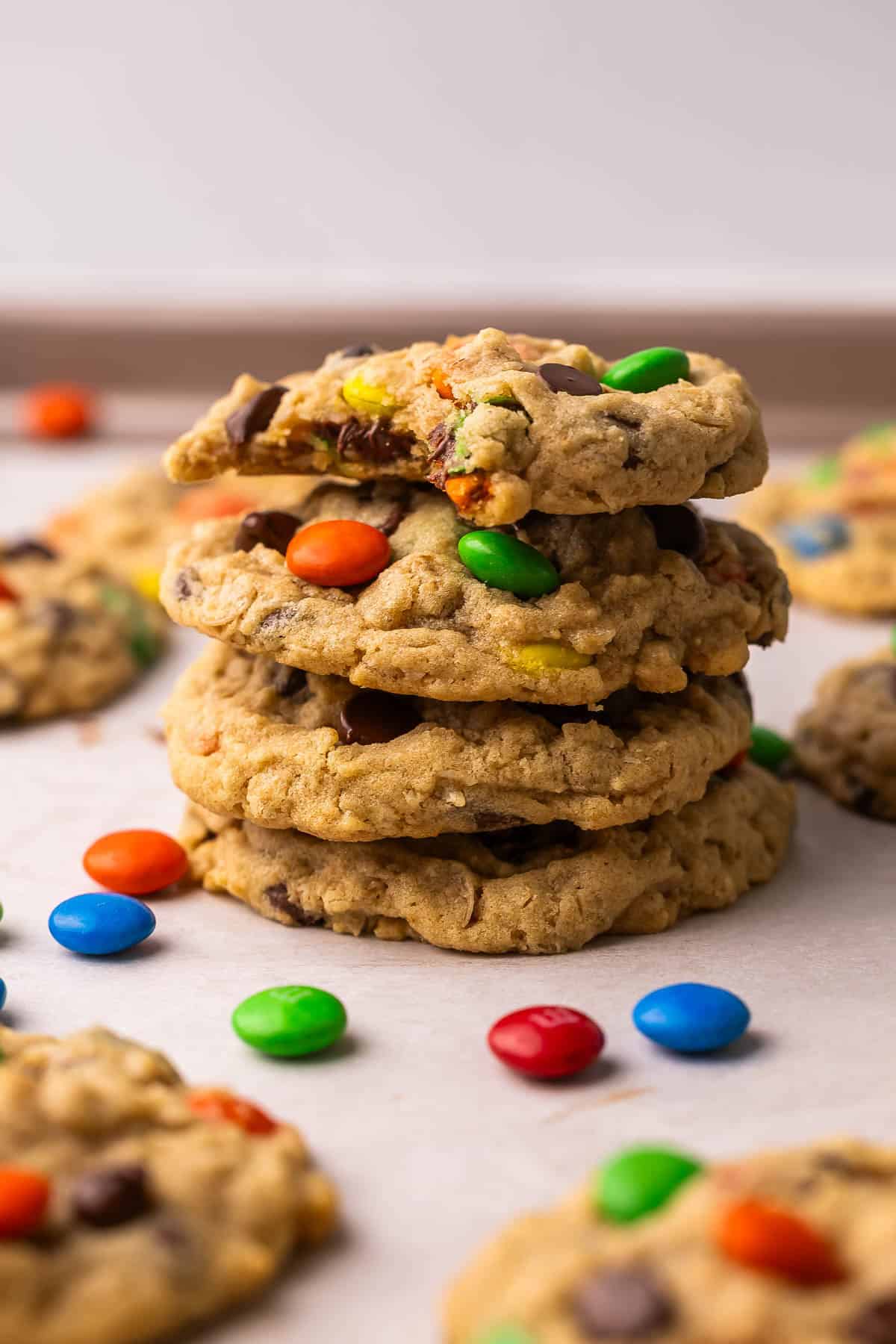 Classic Monster Cookies are loaded with creamy peanut butter, chewy old-fashioned oats, melty chocolate chips, and colorful M&Ms. They're the perfect cookie for those who like a little bit of everything! #cookie #recipe | cookie recipe | cookies recipe | peanut butter cookies | oatmeal cookies | m&m cookies | dessert recipe | baking recipe a stack of monster cookies on parchment paper.