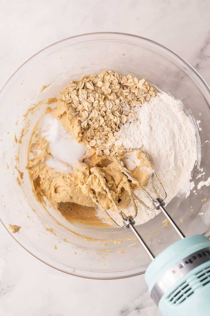 dry ingredients added to cookie dough in mixing bowl.