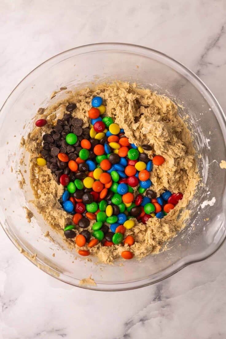 M&M's added to glass bowl filled with cookie dough.