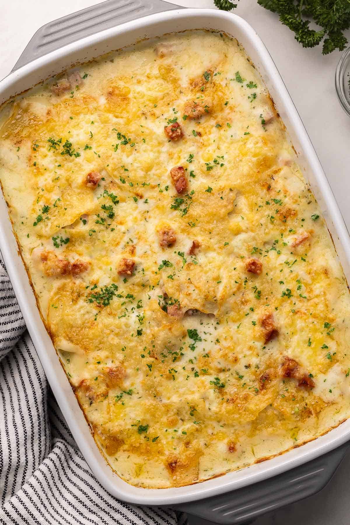 large gray and white pan full of scalloped potatoes and ham.
