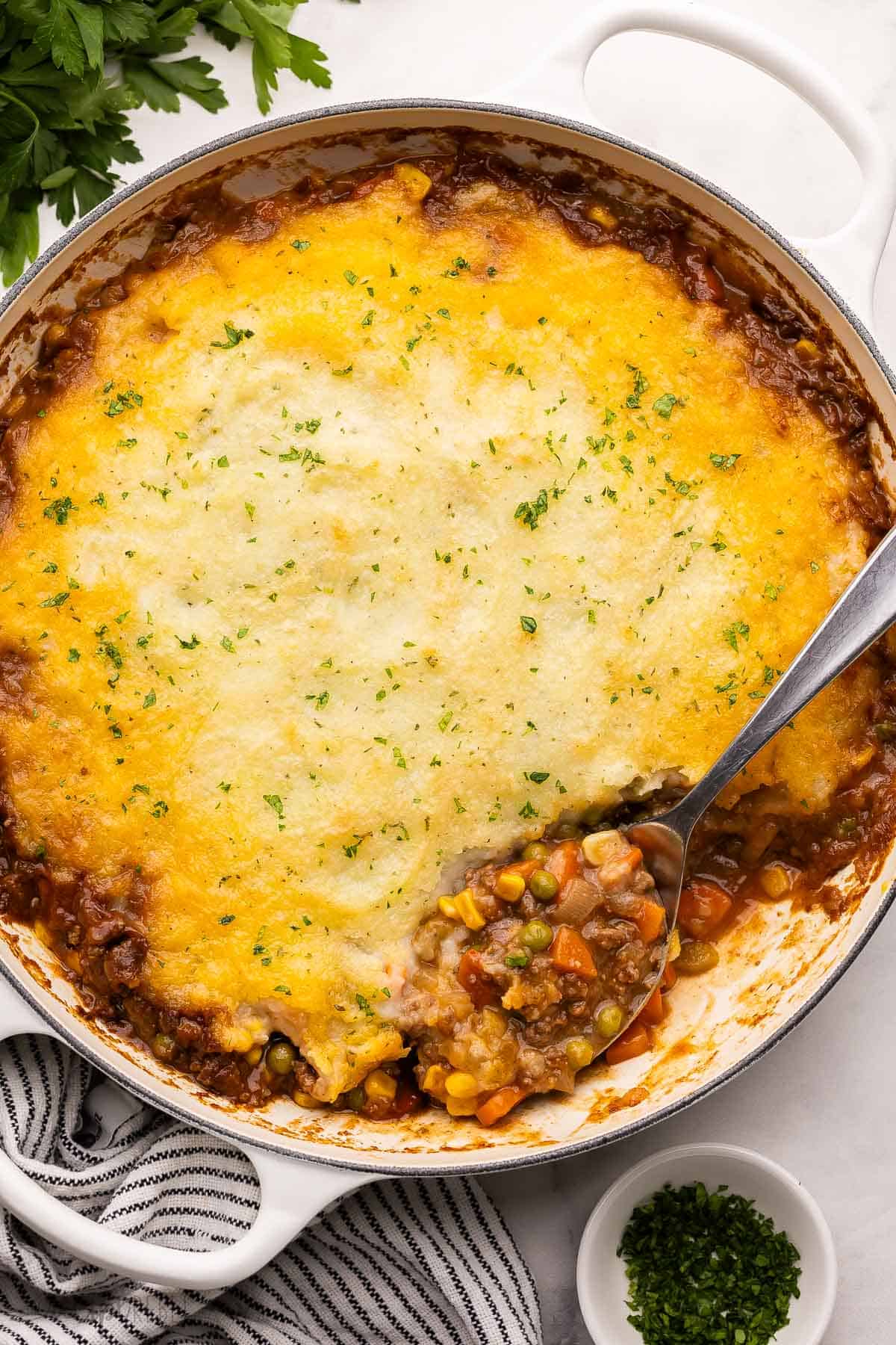 a large spoon scooping shepherds pie out of skillet.