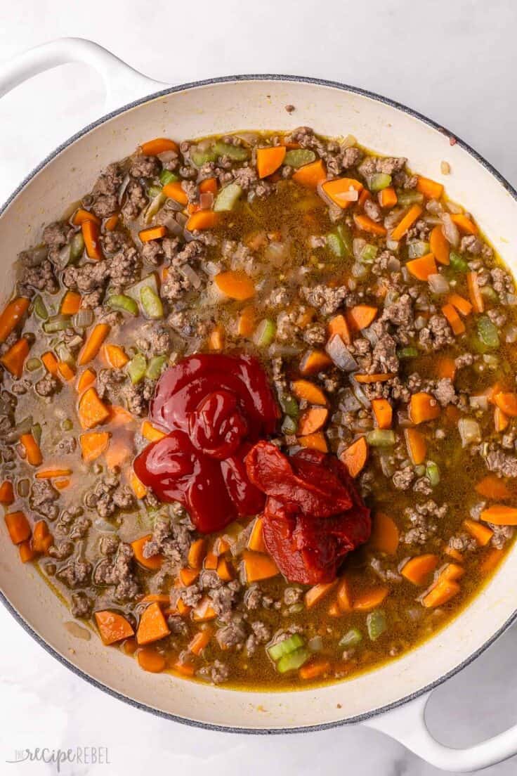 ketchup and other ingredients added to large white skillet.