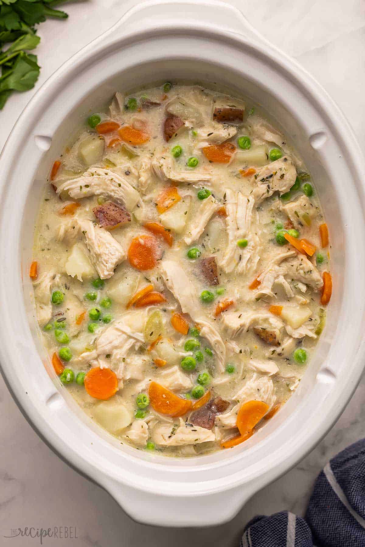 white slow cooker pot full of of garlic parmesan chicken stew.