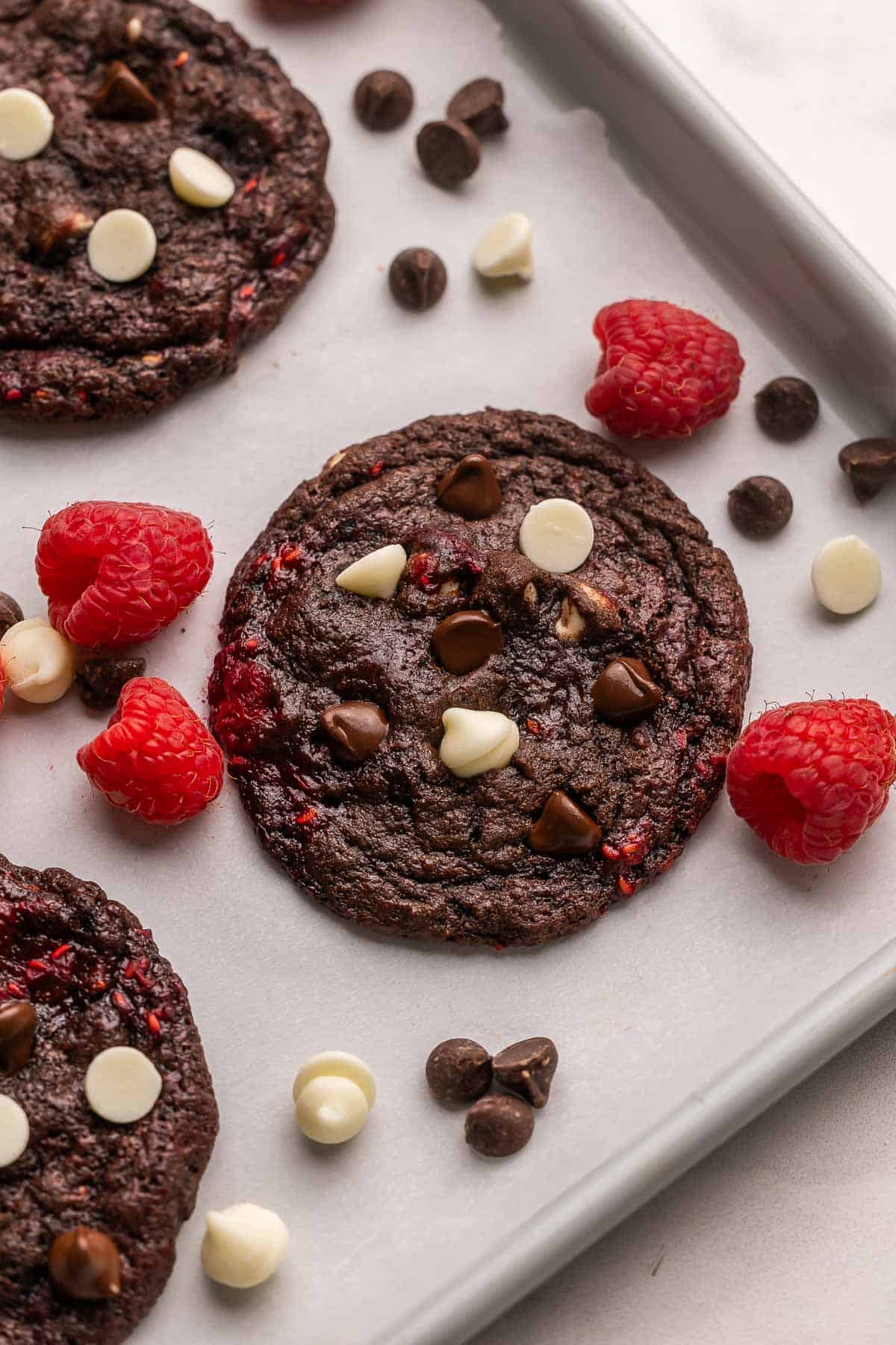 triple chocolate raspberry cookies in a pan with chocolate chips beside.