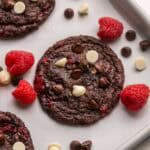 raspberries beside a triple chocolate raspberry cookie.