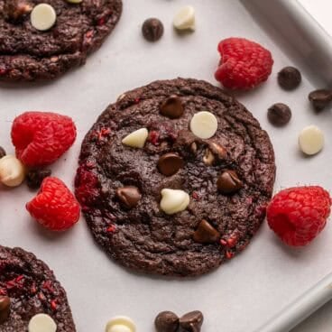 raspberries beside a triple chocolate raspberry cookie.