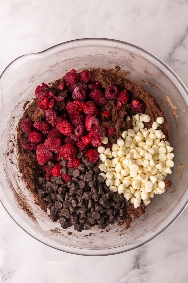 raspberries and chocolate chips added to bowl of cookie dough.