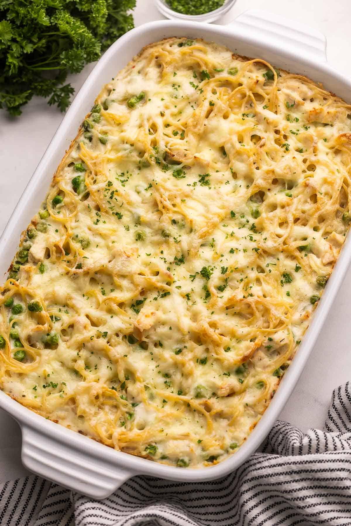 large white dish filled with turkey tetrazzini with parsley beside it.