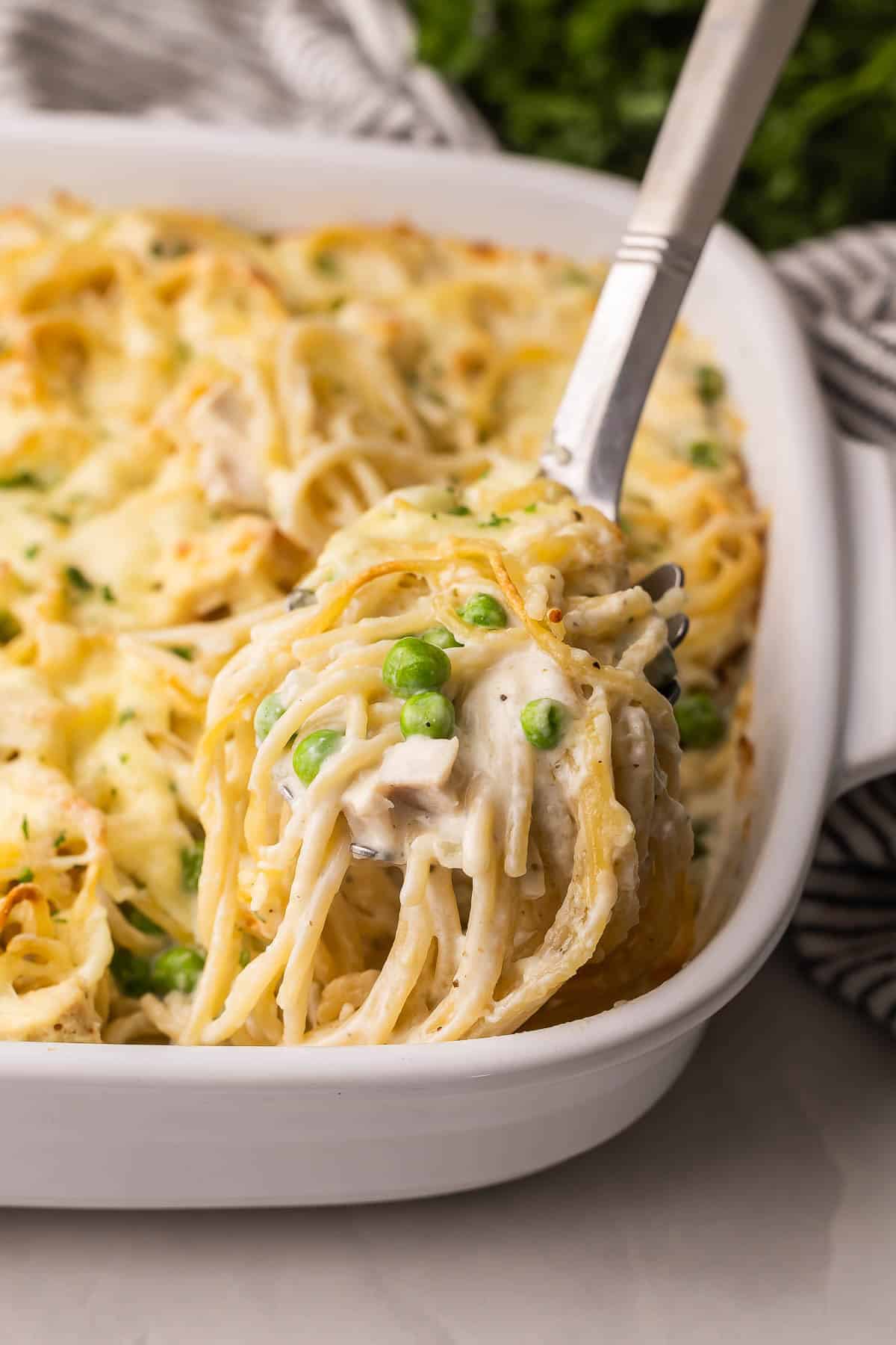 a steel scoop lifting turkey tetrazzini out of white pan.