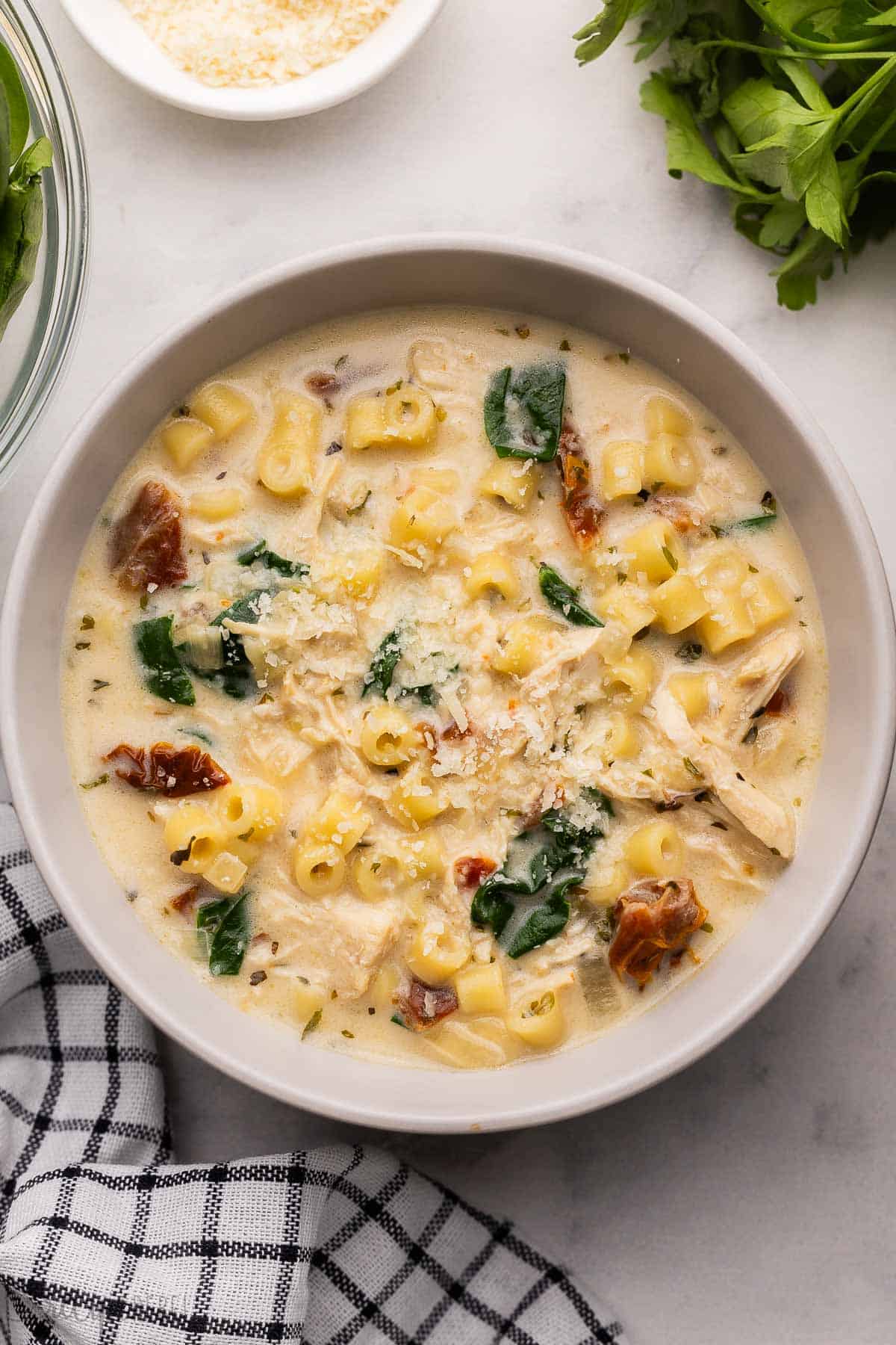 large bowl of tuscan chicken noodle soup topped with parmesan.