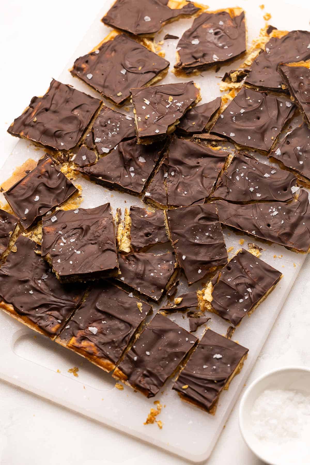 pieces of Christmas crack on a white cutting board.