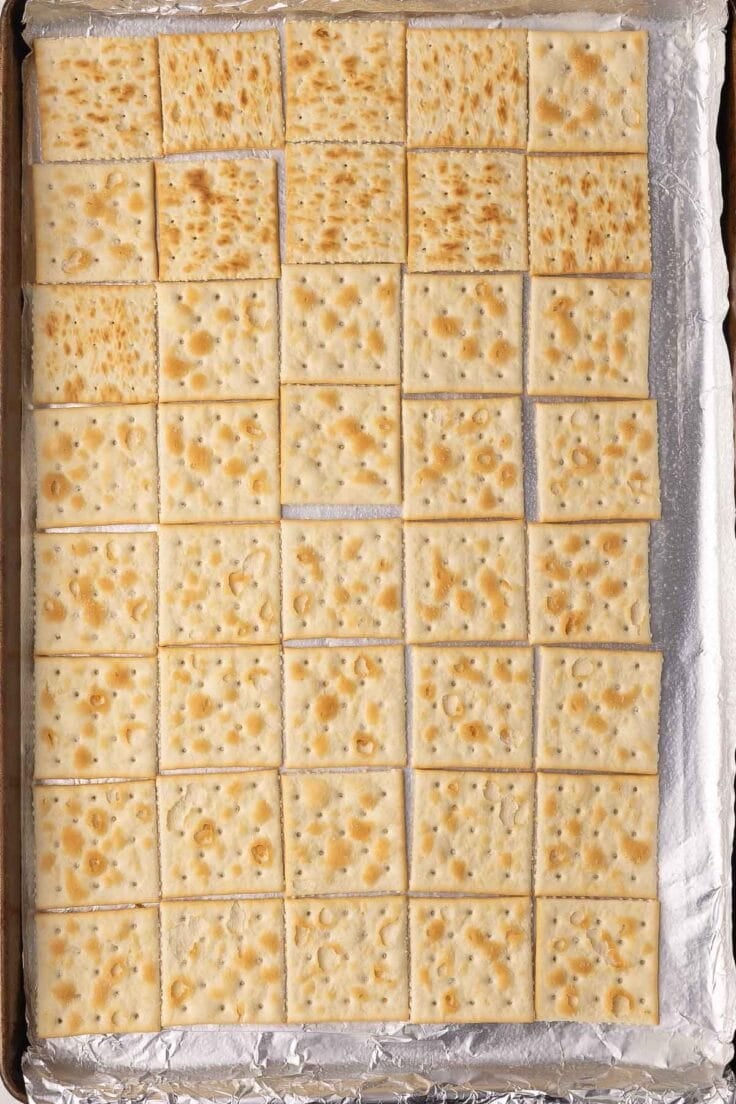 A tray of crackers on a foil lined baking sheet.