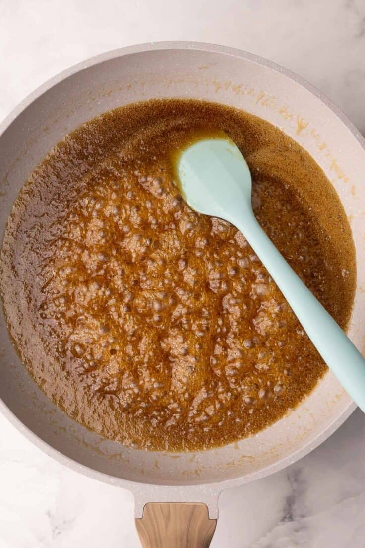 frying pan with melted toffee and blue spatula.