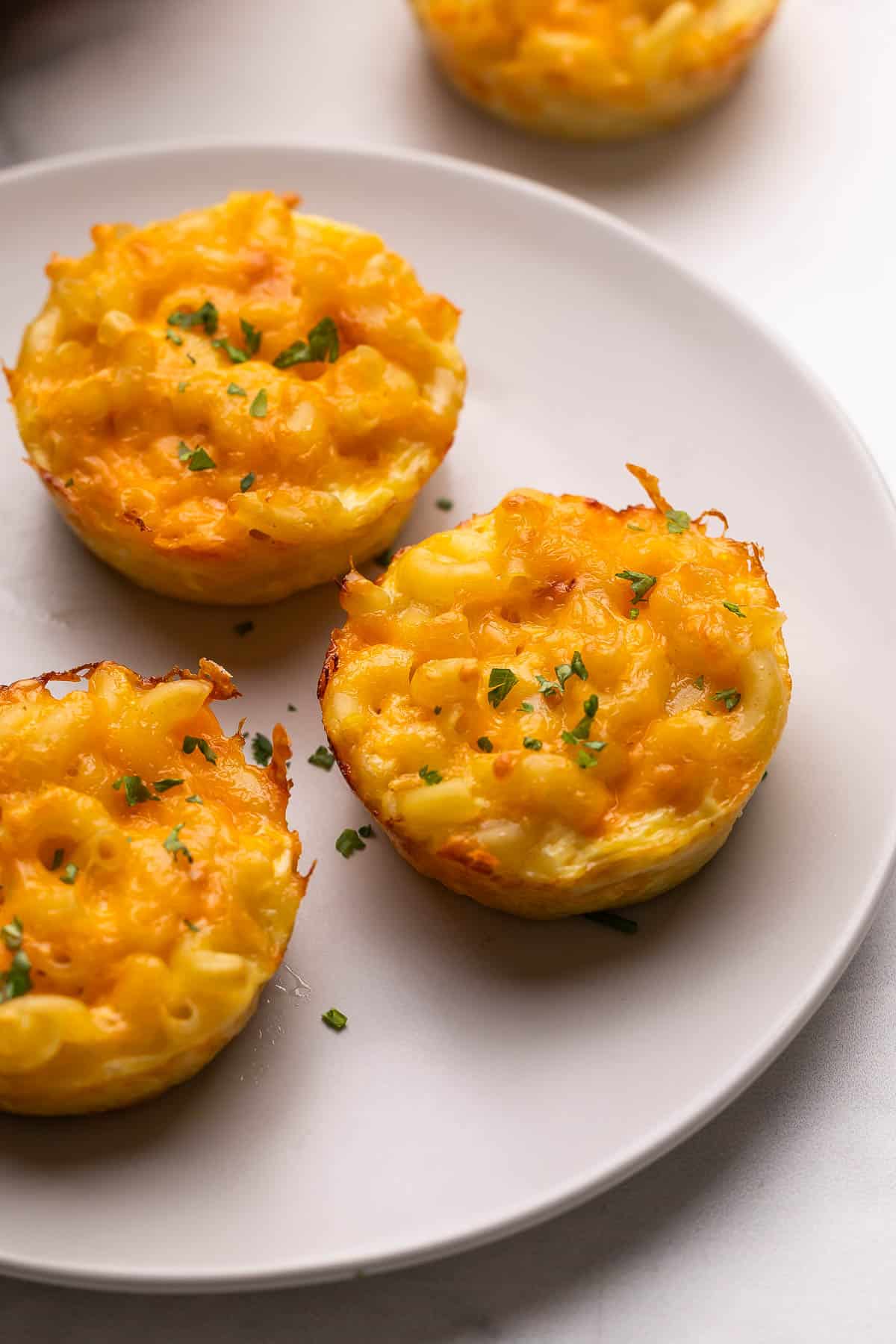 a grey plate with baked mac and cheese cups.