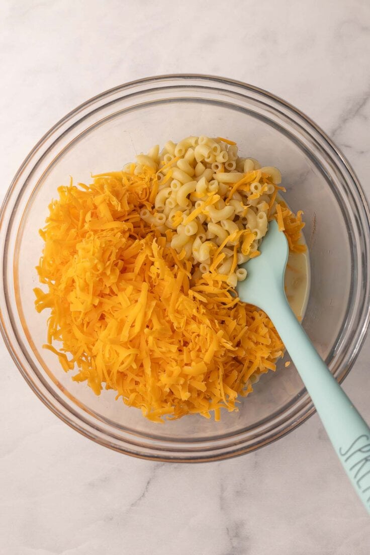 shredded cheese and macaroni in a glass bowl.