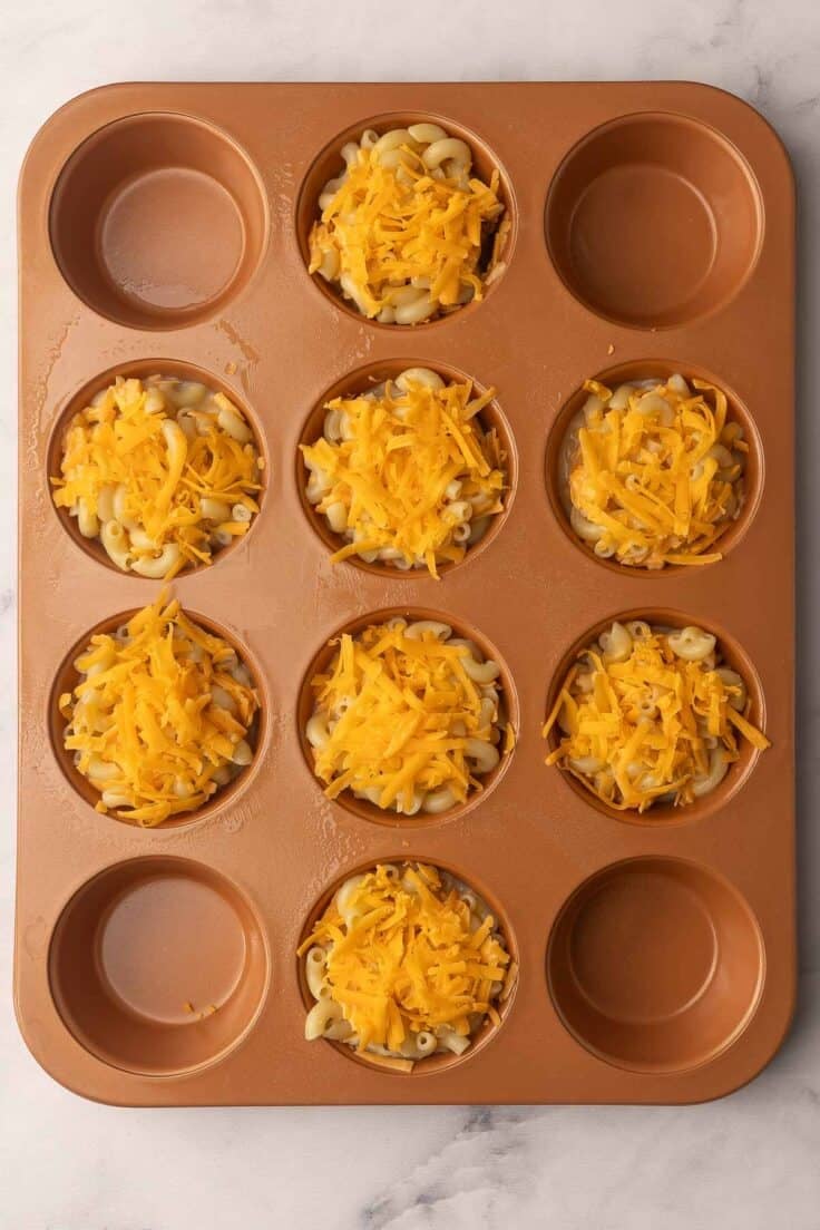 orange muffin pan filled with mac and cheese.