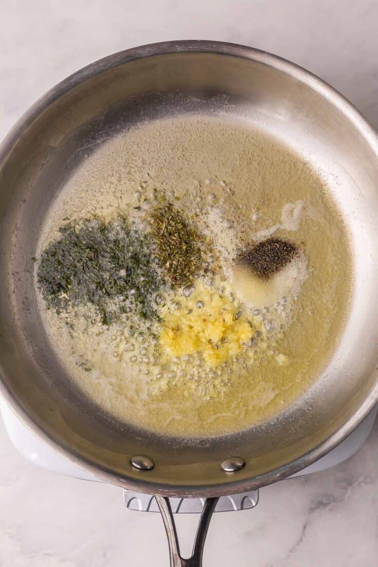 spices added to steel frying pan.