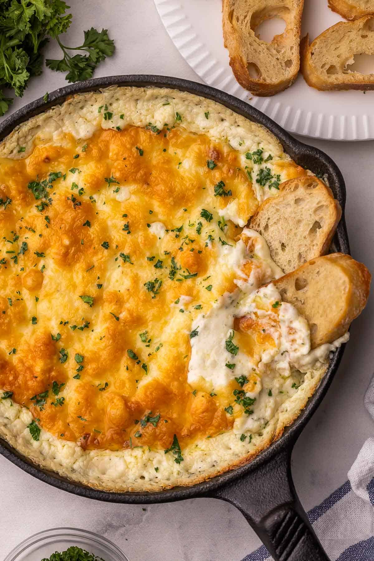 bread dipping into skillet of chicken alfredo dip.