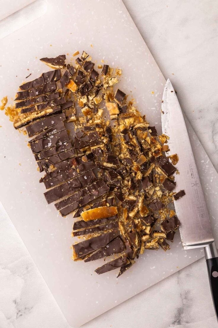 a white cutting board and knife with chopped christmas crack on it.