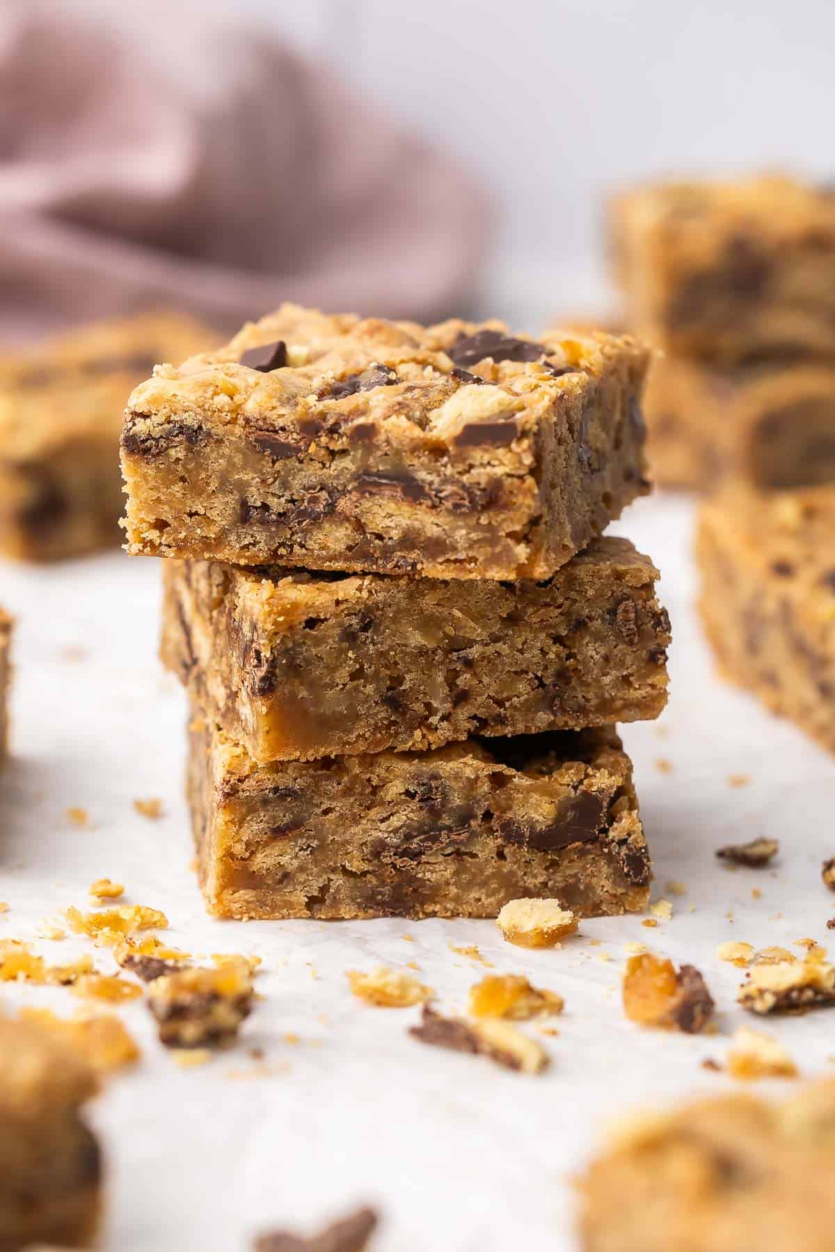 These Christmas Crack Blondies are chewy, buttery bars packed with caramel-chocolate cracker toffee. Made in just 45 minutes, they’re the perfect mash-up of two classic desserts! #dessert #recipe | dessert recipes | christmas recipes | christmas desserts | chocolate | caramel three pieces of christmas crack blondies stacked on each other.