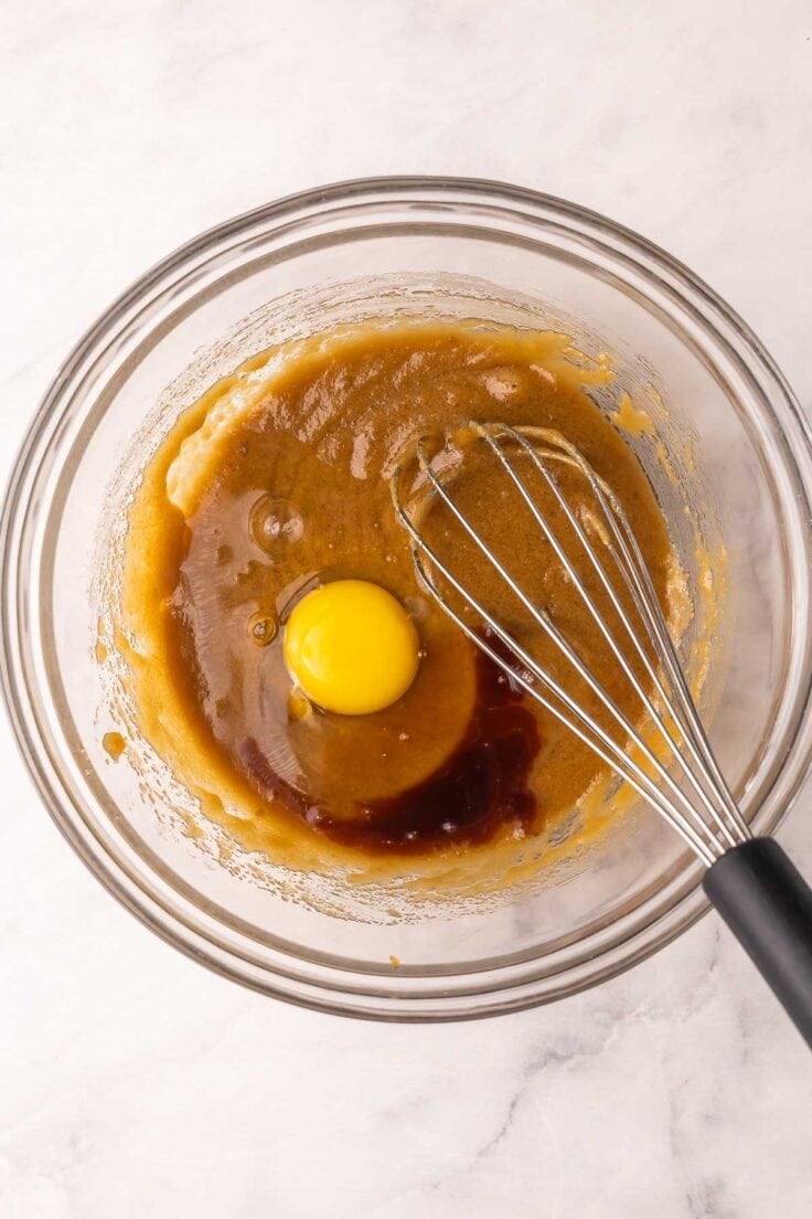 an egg added to other ingredients in a glass mixing bowl.
