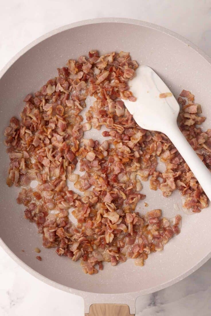 diced bacon frying in a pan.