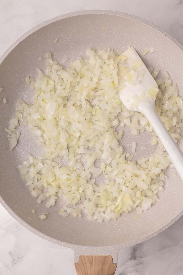 diced onions frying in a pan.