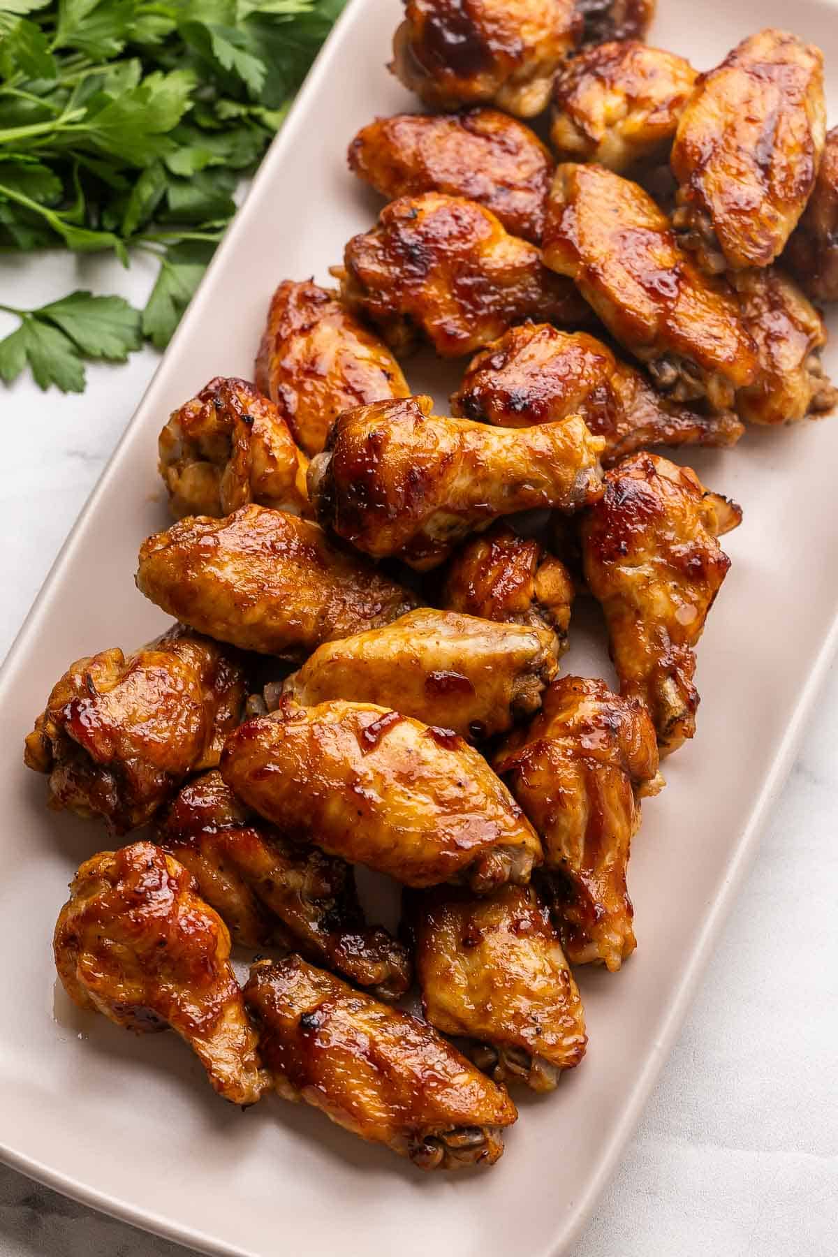 a large tray of chicken wings with parsley beside.
