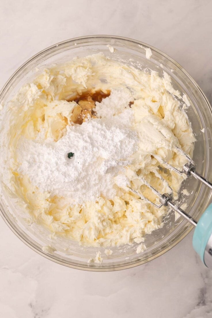 cream cheese and other ingredients being mixed in glass mixing bowl.