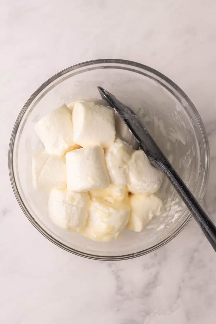 melted marshmallows and a spatula in a glass bowl.