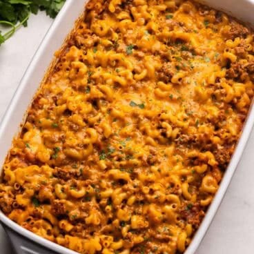 baked cheeseburger pasta in a pan topped with chopped parsley.