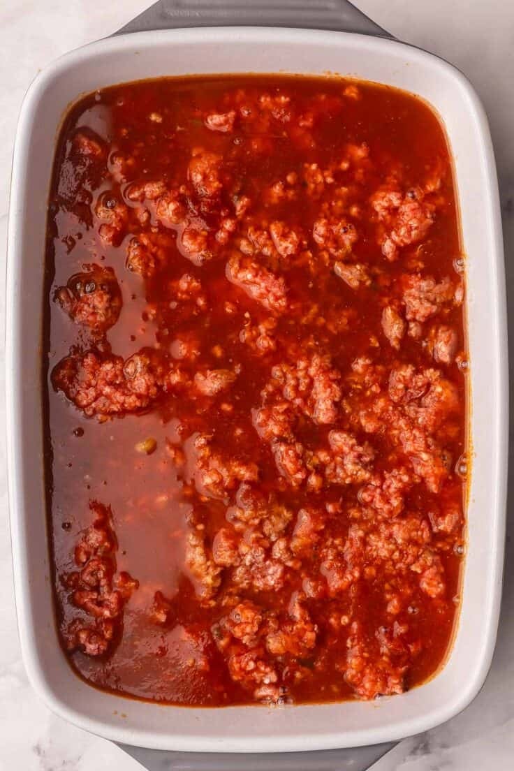 broth added to other ingredients in white baking dish.