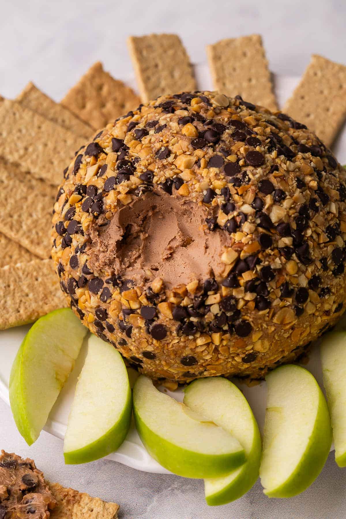 snickers cheeseball on a plate with cracker and apple slices.