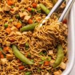 teriyaki chicken ramen bake being lifted out of dish with tongs.