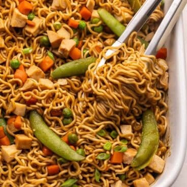 teriyaki chicken ramen bake being lifted out of dish with tongs.