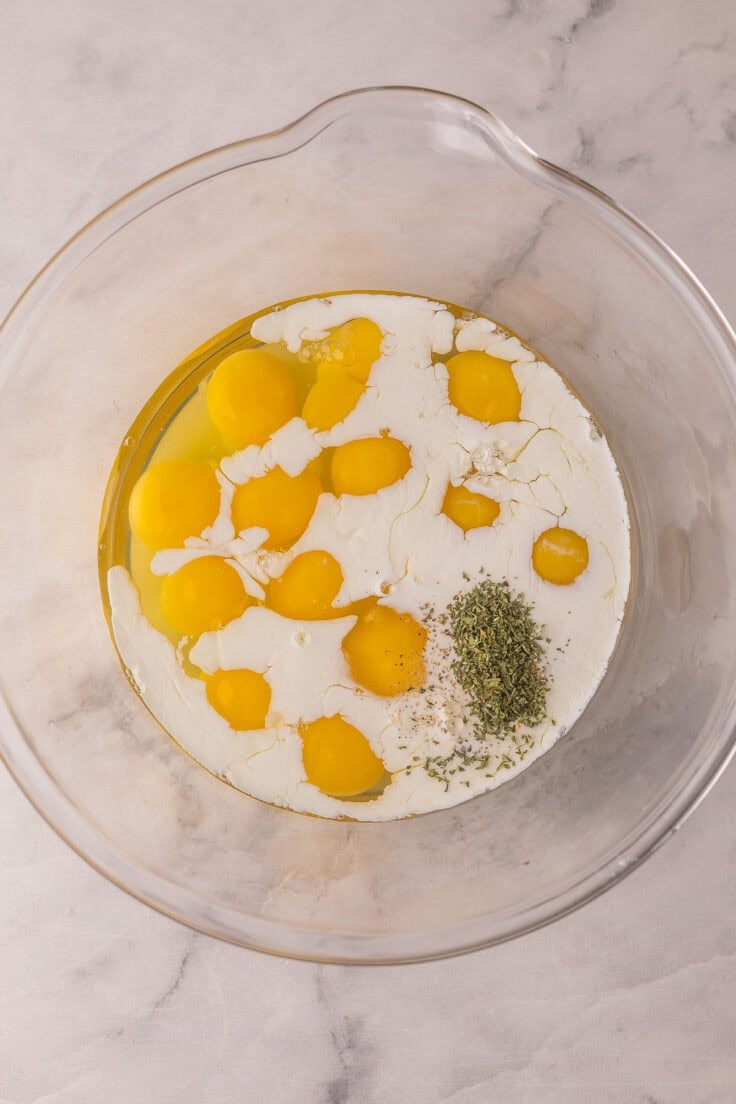 glass mixing bowl with eggs and other ingredients.