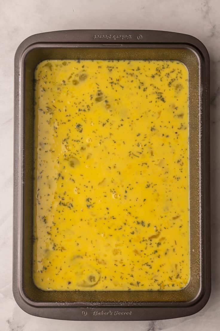 dark grey pan filled with unbaked egg mixture.