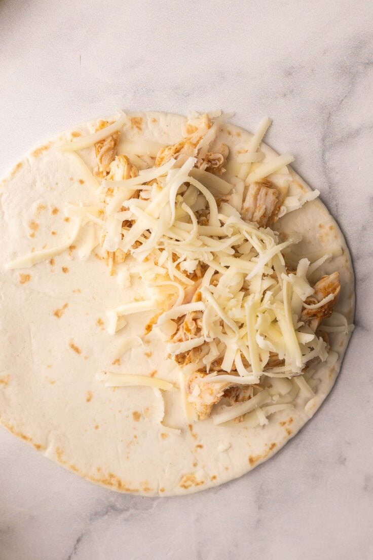assembling chicken tacos with tortillas chicken and cheese.